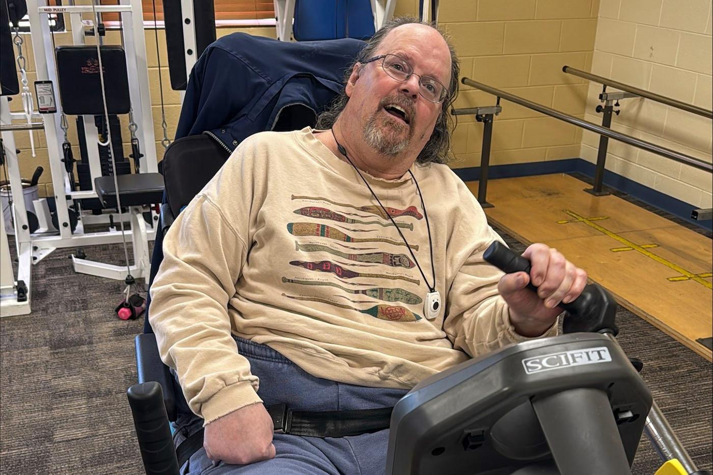 Hilltop Brain Injury Services resident using exercise equipment in the campus fitness room.